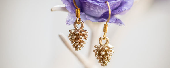 tini tiny gold pine corn earings on hanging a purple flower