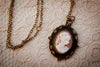 Cameo Necklace peach pink and white on brass filigree charm pendant with chain on lace backdrop