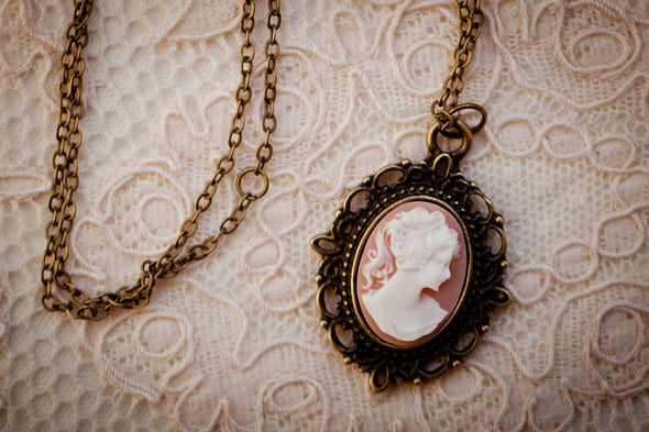 Cameo Necklace peach pink and white on brass filigree charm pendant with chain on lace backdrop
