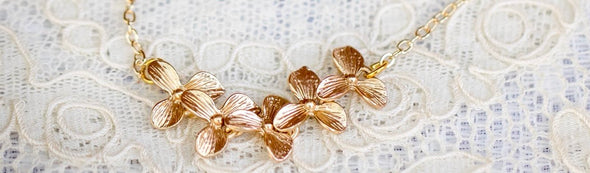 5 orchid blossoms in a row necklace on a lace background