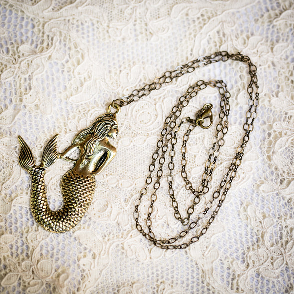 brass mermaid charm necklace on lace background