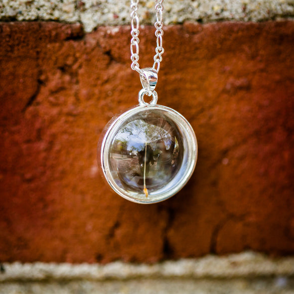 sterling silver dandelion seed necklace with single seed, red brick background