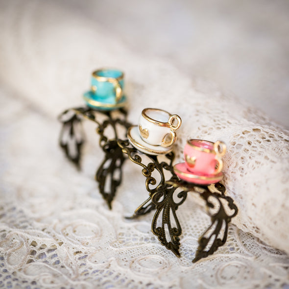 three vintage dollhouse tea cup rings blue white pink with hearts on brass bands on lace backdrop