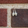 tiny silver pine corn earrings hanging on brick wall