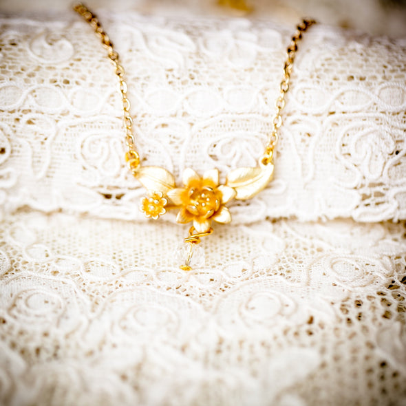the evelyn lotus flower gold necklace on lace background front view