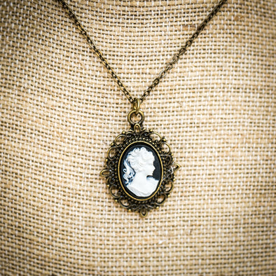 Cameo Necklace black and white on brass filigree charm pendant with chain on lace backdrop
