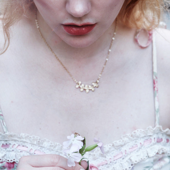 really pretty model with pink hair wearing gold orchid blossom necklace and a leaf wrap ring with pink hair