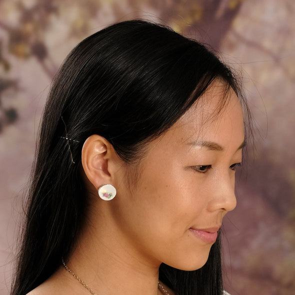 Beautiful woman wearing floral pattern china plate tea set stud earrings with faint smile