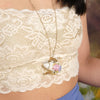 Beautiful model wearing floral vintage china teapot necklace  on chain wearing lace crop top against tree backdrop