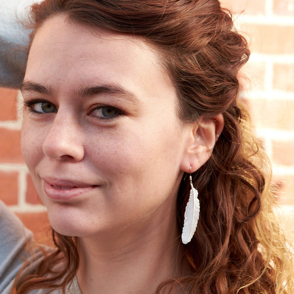 Beautiful model wearing silver feather earring