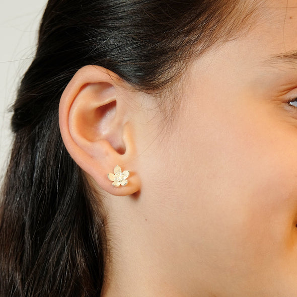Beautiful teenager in white shirt wearing silver lotus earrings and necklace side view
