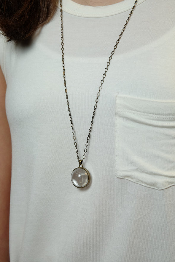 silver plated dandelion seed necklace worn by teenage girl with white shirt