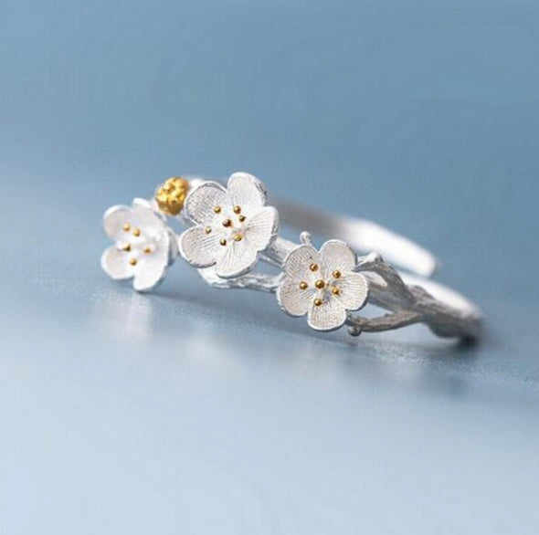Plum Blossom Ring with sterling silver and 18k gold buds adjustable on a blue background
