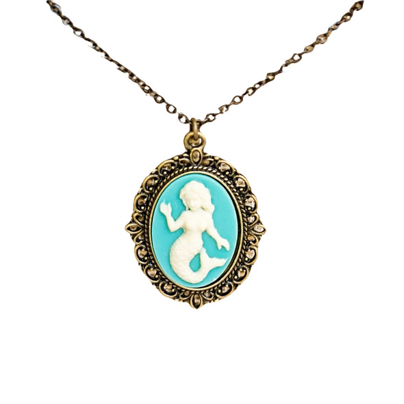 White resin mermaid on a aqua and teal  background in a brass filigree cabachon setting on a white background cameo