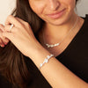 cherry blossom necklace and earrings and bracelet and ring on a hand with a black dress 