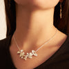 closeupofasilverorchidpetalnecklaceonamodelwearingablackshirtandorchiddangleearrings