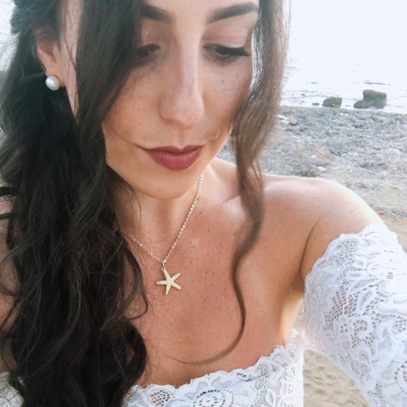 beautiful bride maid wearing a gold star fish necklace on a beach in Cyprus lace crop top pearl earrings 