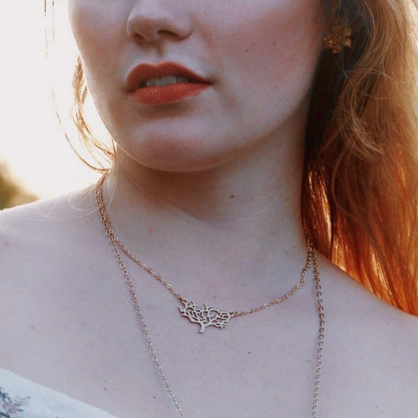model in a field weraing a wishbone and tree of life necklace
