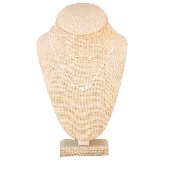 single bird on branch necklace on linen neck on white backdrop silver and gold branch necklace