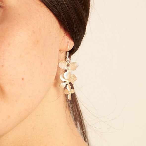 smiling israeli model wearing a orchid 5 petal and blossom necklace and matching earrings 