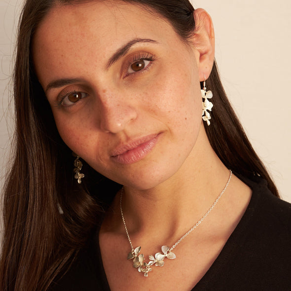 smiling israeli model wearing a orchid 5 petal and blossom necklace and matching earrings 