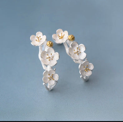 sterling silver plum blossom earrings on blue background